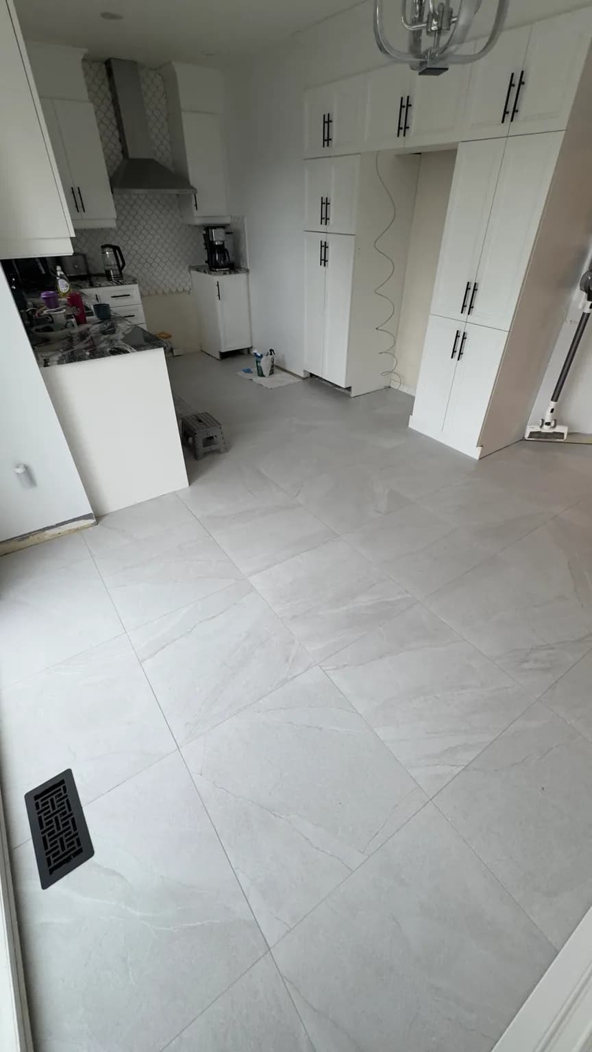 Completed 24 × 24 porcelain floor in a residential kitchen in Laval-des-Rapides.