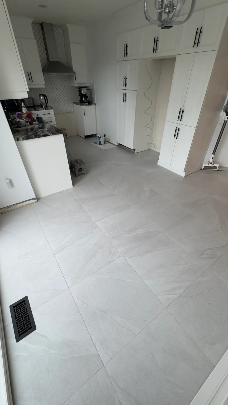 Completed 24 × 24 porcelain floor in a residential kitchen in Laval-des-Rapides.