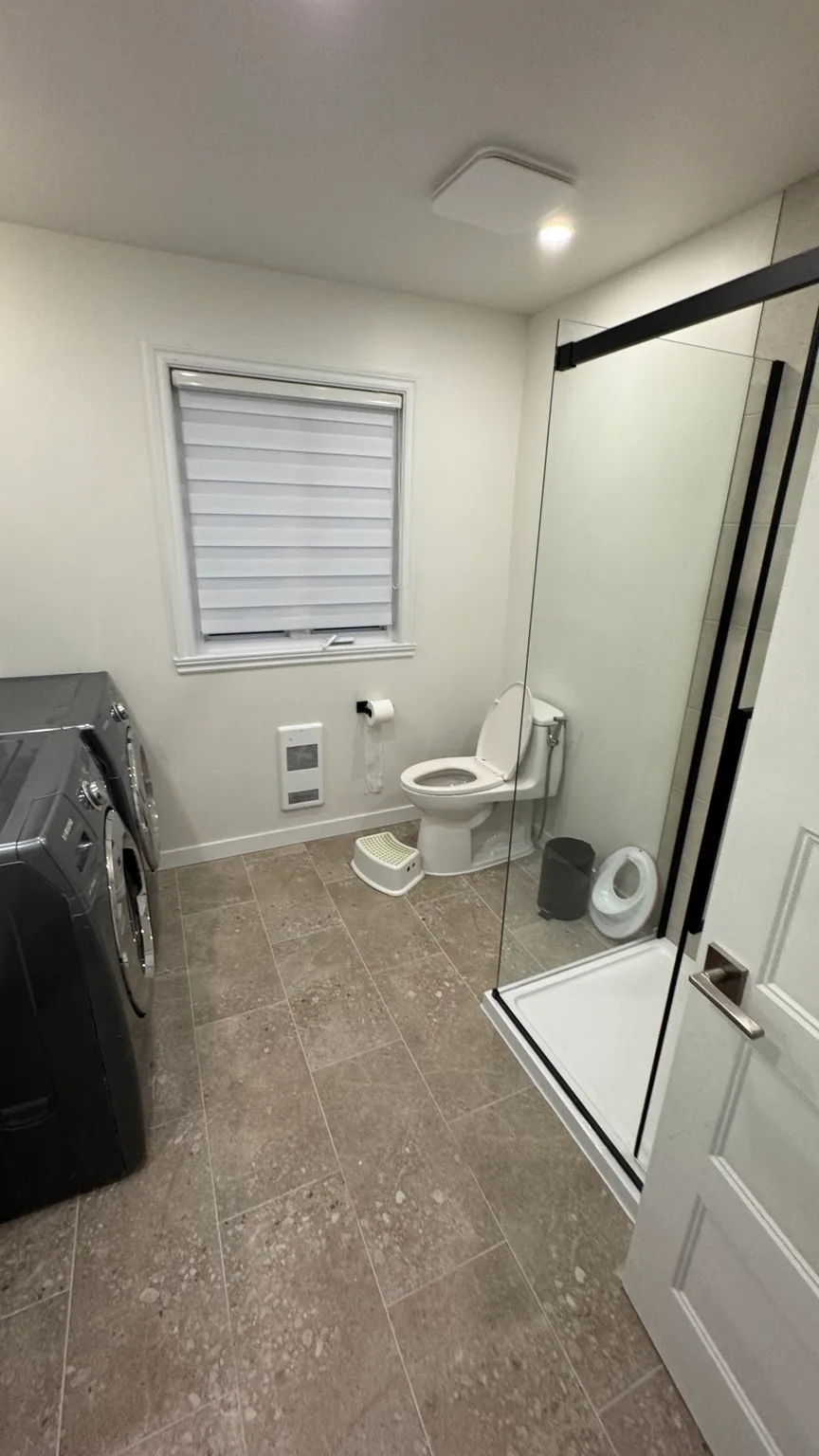 Renovated shower with acrylic base, ceramic wall tile and glass panels.