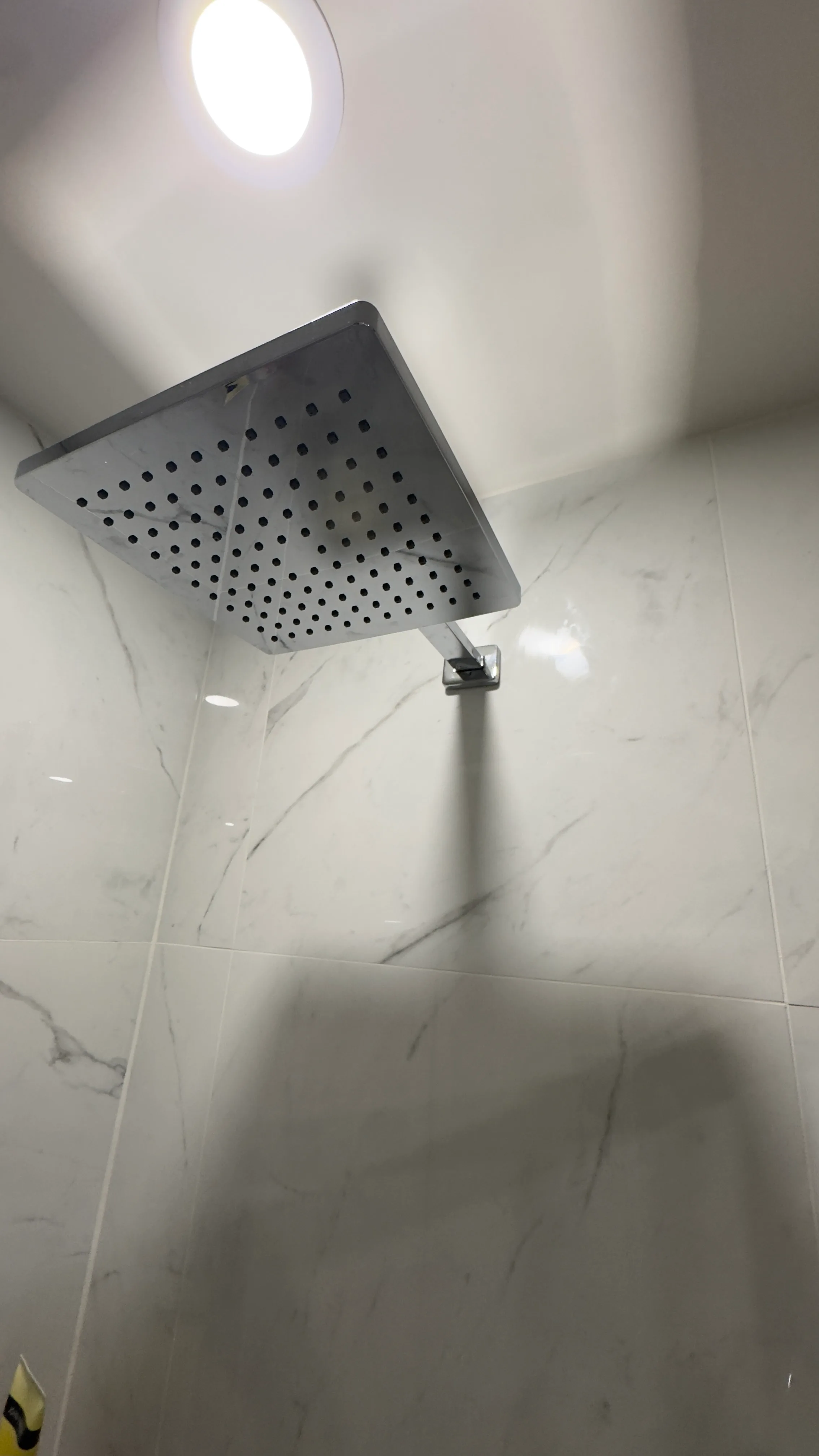 Rain shower head detail in the completed marble-look porcelain shower.